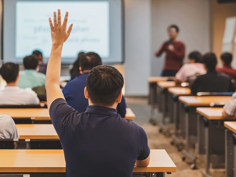 classroom full of students raising their hands